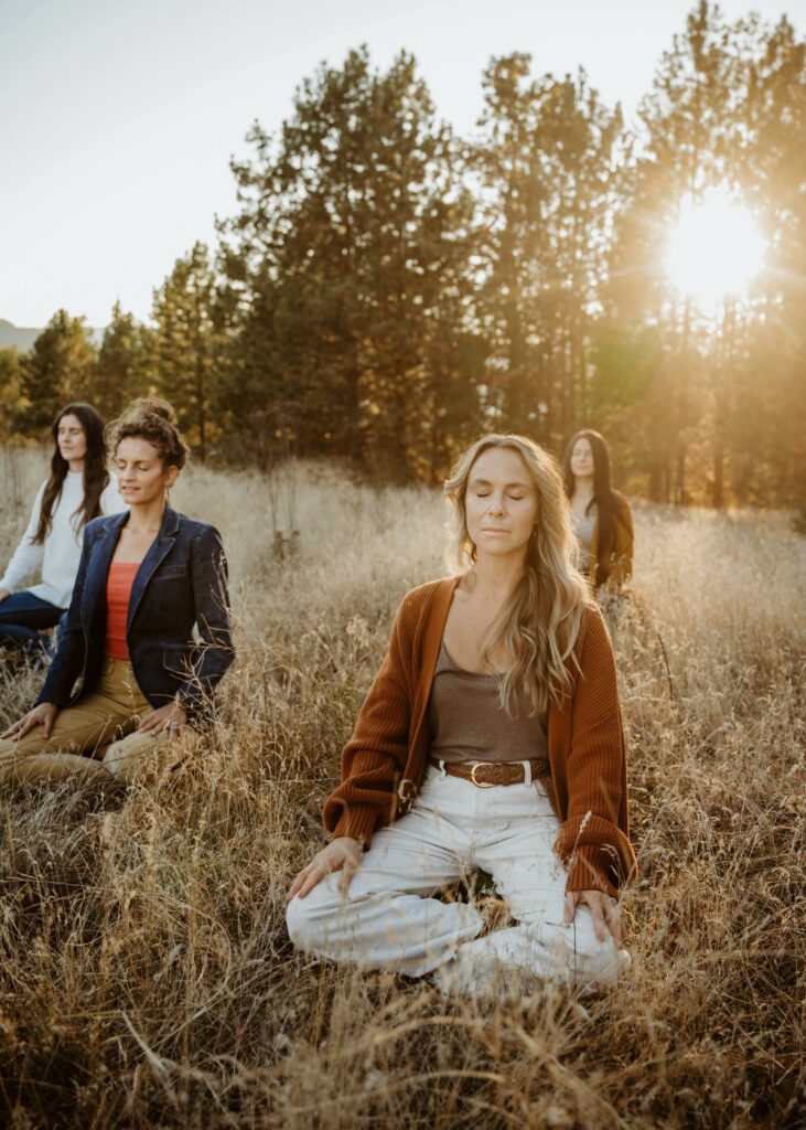 A serene outdoor meditation session with a group of women in an autumn park setting.