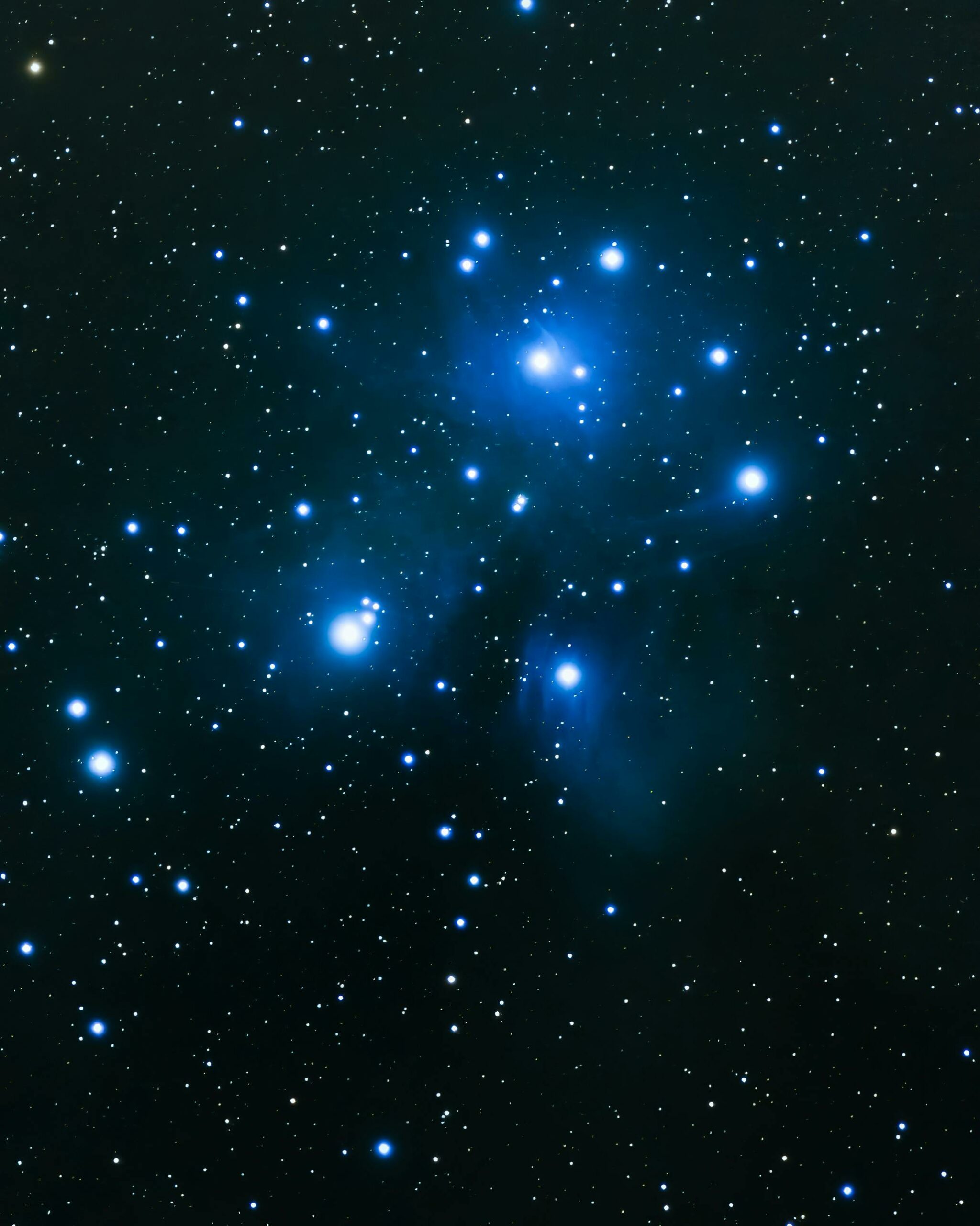 Capture of the Pleiades star cluster, showcasing its luminous blue stars in a vast night sky.