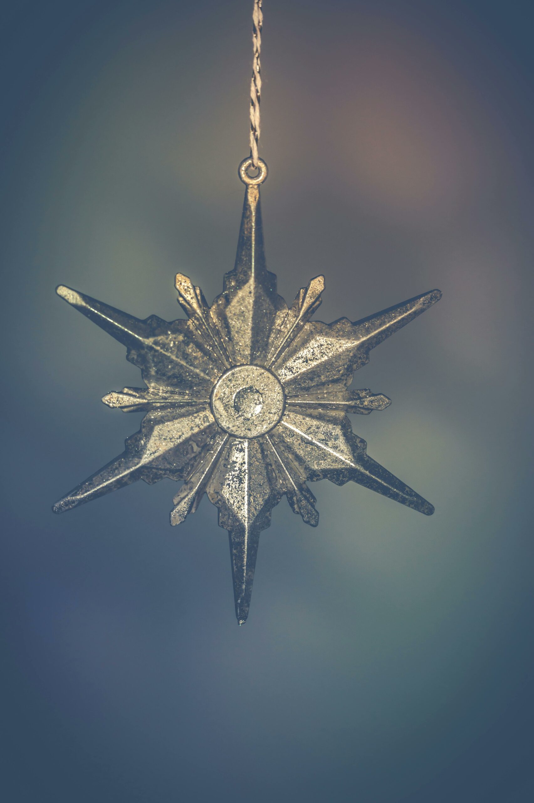 Close-up of an elegant metallic star pendant with intricate design, hanging on a chain.