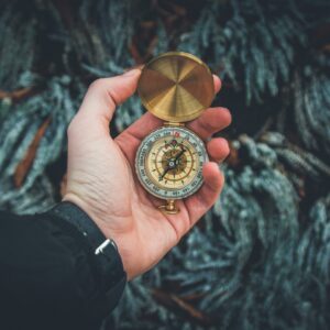 A close-up shot of a hand holding a vintage compass against a natural background.