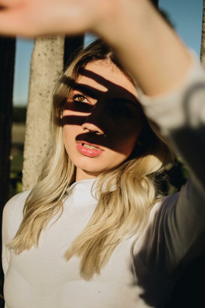 Artistic portrait of a woman with dramatic shadow patterns across her face.