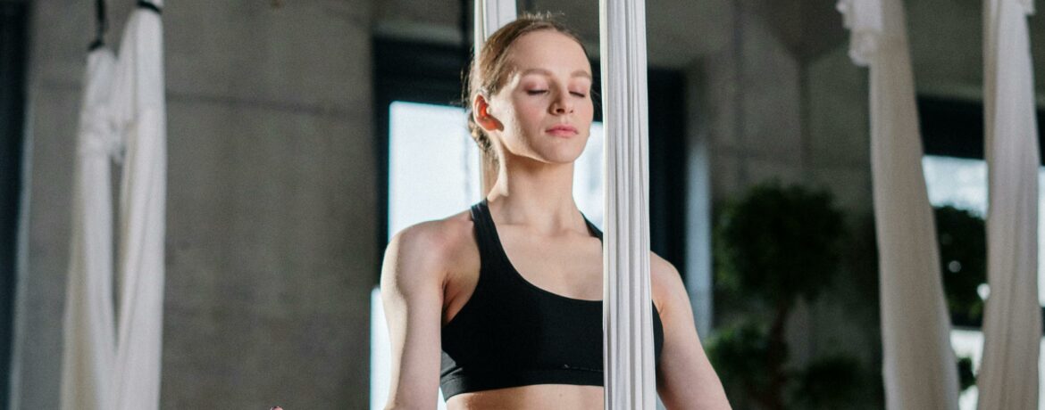 Woman practices aerial yoga in a modern studio, achieving harmony and balance.