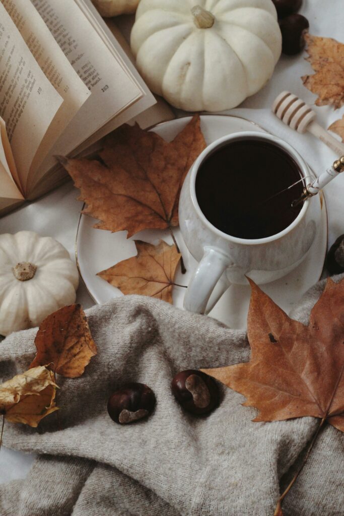 Warm and inviting autumn still life featuring a cup of tea, pumpkins, and fallen leaves.