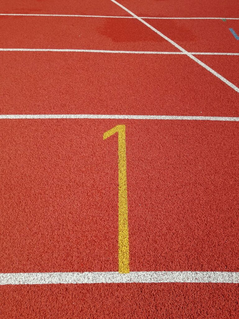 Close-up of red athletic track with a yellow lane number, symbolizing sports and fitness.